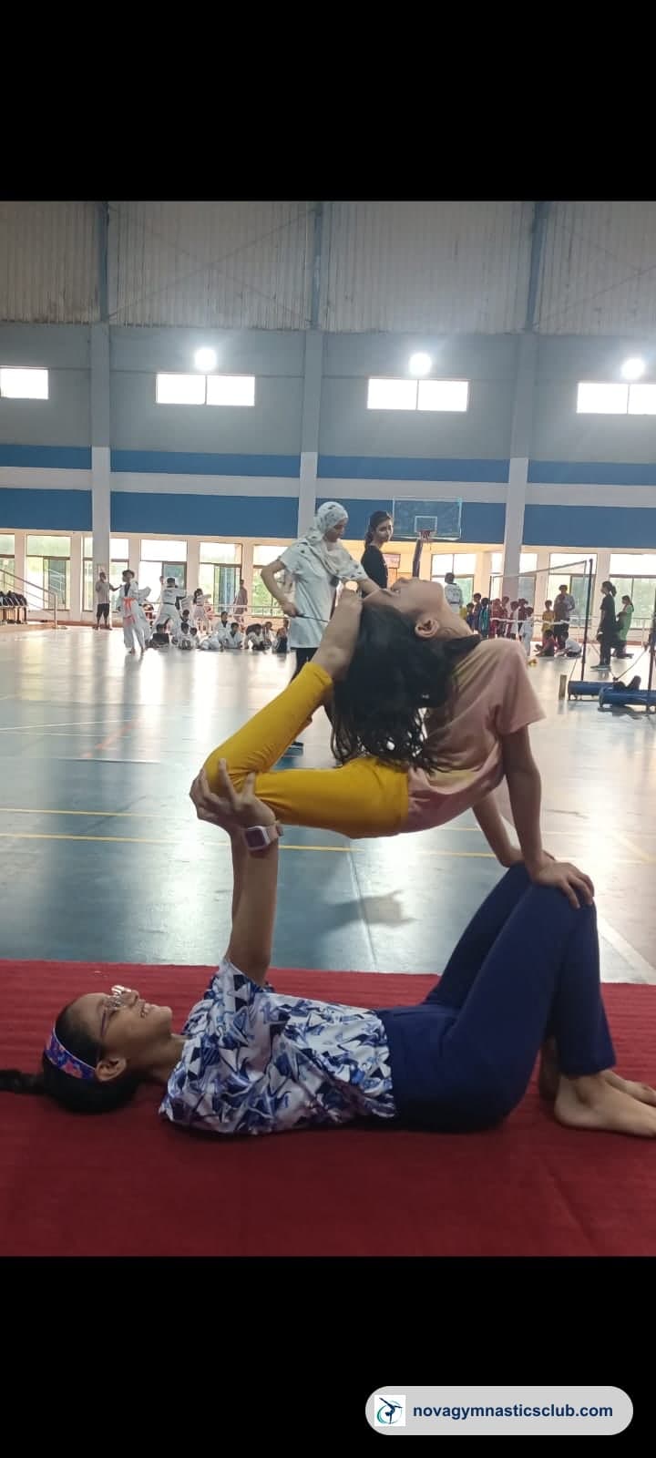 Two girls practising a partner balance in the indoor training hall