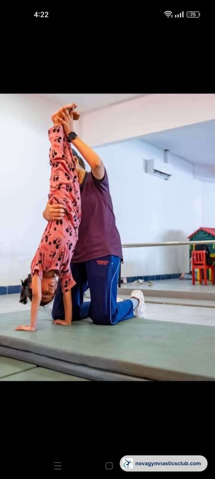 A coach spotting a young girl in a handstand